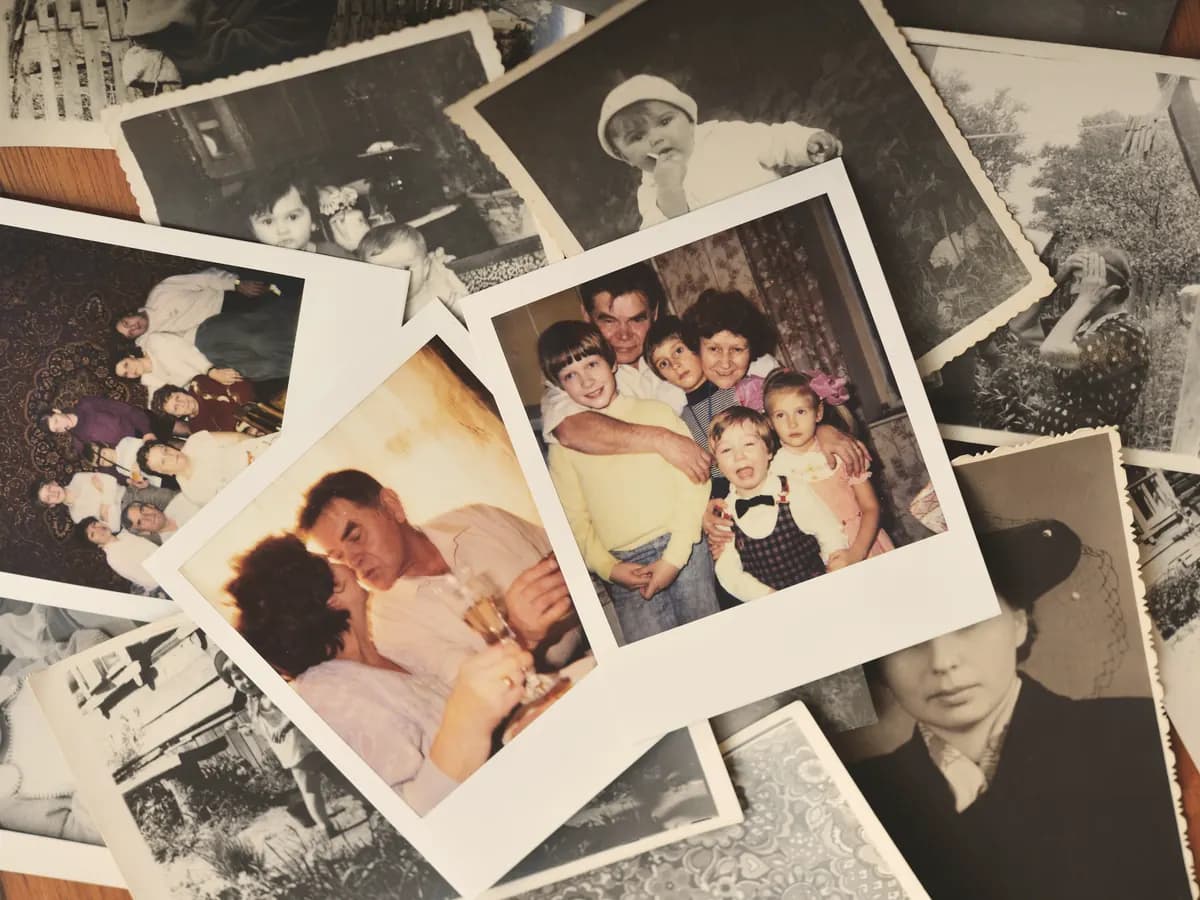 Loose black-and-white and color family snapshots spread across a table